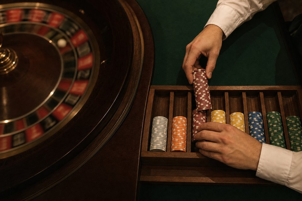 A dealer's hands taking payout chips from a wooden chip rack at the table edge (AI-generated image)